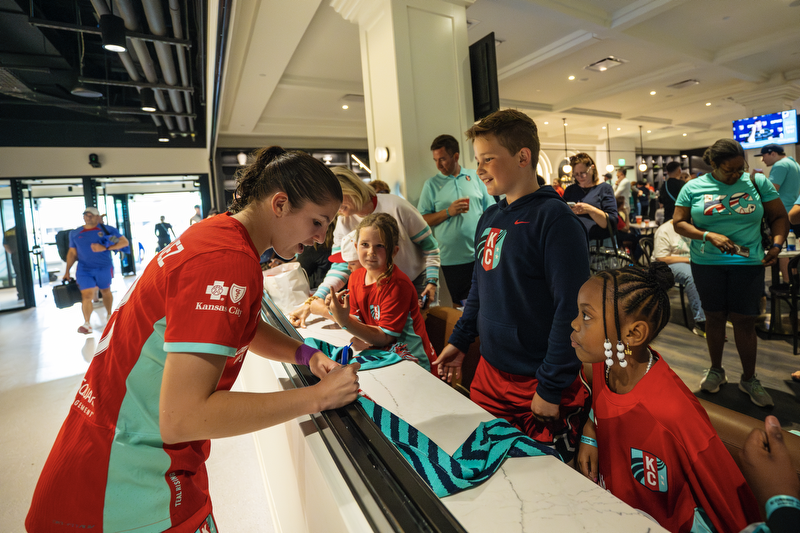 Fans getting autographs from players in their pitch club seats.