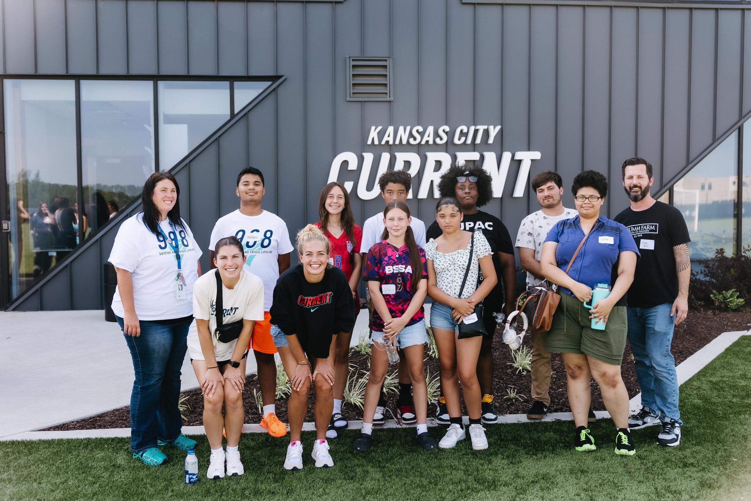 Students and KC Current players take photo in front of training facility at teal talks event.